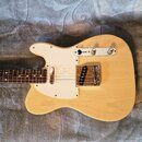 Světle žlutá elektrická kytara typu Telecaster s bílým pickguardem. Na kovovém krytu mostu je vidět nápis "Fender". Kytara má hnědý hmatník s bílými…