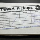 Fotografie zobrazuje štítek s nápisem TOMA Pickups a textem Výroba a opravy elektromagnetických snímačů pro kytary a baskytary. V tabulce jsou u pozi…