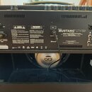Zadní strana černého kytarového komba s nápisem MODEL MUSTANG™ GTX100 a logem Fender. Jsou zde vidět různé konektory, včetně USB, LINE OUT a FX SEND/…