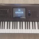 Černý klavír s nápisy KORG a KRONOS MUSIC WORKSTATION na displeji i v pravé části korpusu. Nástroj disponuje ovládacími prvky v horní části a standar…
