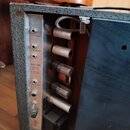 Zadní strana kytarového komba s kovovým zadním panelem a šedým potahem. Na panelu jsou vstupy s nápisy MICROPHONE a INSTRUMENTS, přepínač FOOT SWITCH…