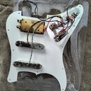 Bílá pickguard pro elektrickou kytaru s instalovanou elektronikou a třemi snímači. Horní snímač je v mosazném provedení, spodní dva jsou chromované s…