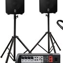 Dva černé reproduktory s logem YAMAHA jsou umístěny na černých kovových stativech. V popředí je černý mixovací pult s bílými popisky a ovládacími prv…