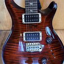 Elektrická kytara s tmavě hnědým plamenovým javorovým povrchem těla. Je vybavena dvěma humbuckery s bílými rámečky a chromovaným mostem. Na hmatníku…