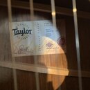 Fotografie zachycuje vnitřní štítky kytary. Na bílém štítku je logo Taylor Quality Guitars, podpis Andy Powers a nápis ANDY POWERS Master Guitar Desi…