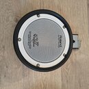 Kruhové elektronické bubnové plochy s bílým pleteným povrchem a černým gumovým okrajem. Na povrchu jsou nápisy Roland, MESH HEAD™ made by REMO a logo…