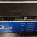 Černý rackový audio interface značky MOTU, který leží ve své původní krabici. Na předním panelu jsou vidět dva kombinované konektory, ovládací prvky…