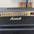 Černý kytarový kombozesilovač s nápisem Marshall na předním textilním krytu. Horní ovládací panel je stříbrný s nápisy JCM600 VALVE GUITAR AMPLIFIER,…
