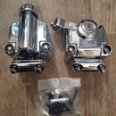 Dvě chromované kovové svorky na bubnový hardware. Pravá svorka nese nápis Pearl. Vedle nich je v průhledném plastovém sáčku sada černých kovových díl…