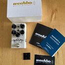 Bílý efekt pedál s nápisy BASTARD a LOW END DISTORTION. Na horní části jsou ovládací knoflíky s popisky LEVEL, VOICE, GAIN, TREBLE, MIDDLE a BASS. So…