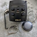 Černý předzesilovač s ovládacími prvky a nápisy. Na zařízení jsou vidět popisky - volume +, tuner, blend, batt.low, pick, tap, tap/eq a pick/eq, v do…