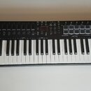 Černý MIDI kontrolér s klávesnicí. V levém horním rohu je bílý nápis M-AUDIO a v levém dolním rohu označení OXYGEN PRO 49. Horní panel obsahuje někol…
