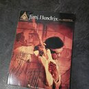 Fotografie znázorňuje sešit s notami. Na obálce je fotografie Jimiho Hendrixe s kytarou a nápisy „GUITAR“, „Jimi Hendrix LIVE AT WOODSTOCK“ a v dolní…