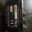 Zadní strana černé kytarového efektu v kovovém šasi s texturovaným povrchem. Na bílé nálepce je uveden nápis AMT electronics, model TS-2 a označení T…