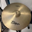 Zlatý kovový činel s viditelným brusením. V horní části je nápis „A MEDIUM THIN CRASH“ a pod ním označení „20"/51CM“. Ve spodní části je černé logo „…