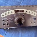 Stříbrný monitorovací kontrolér s nápisy XENYX CONTROL 1 USB a logem behringer. Zařízení obsahuje velký centrální ovratový knoflík Volume, několik me…