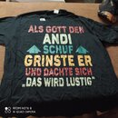 Černý tričko s barevným textem v němmeckém jazyce: „ALS GOTT DEN ANDI SCHUF GRINSTE ER UND DACHTE SICH „DAS WIRD LUSTIG““. Text je doplněn dvěma modr…