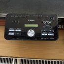 Černý elektronický modul s nápisy YAMAHA a DTX drums. Na spodní hraně je uveden text DRUM TRIGGER MODULE DTX502. Zařízení obsahuje řadu tlačítek s po…
