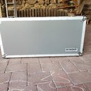 Stříbrný hliníkový kufr s kovovými rohy a hranami. V pravém dolním rohu je bílý štítek s nápisem ROCKBOARD by Warwick. Povrch kufrů vykazuje mírné zn…