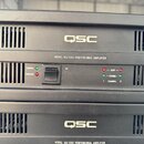 Detailní pohled na přední panel černého rackového zesilovače s nápisem QSC a MODEL ISA 1350 PROFESSIONAL AMPLIFIER. Jsou zde vidět ventilace, vypínac…