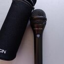 Černý dynamický mikrofon s mřížkou a doprovodným černým zipovým pouzdrem. Na těle mikrofonu je nápis TCHELICON, tlačítko s označením Mic Control a v…