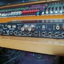 Černý rackový audio rozhraní s nápisem FW 400. Zařízení obsahuje různé konektory, včetně MIDI I/O, ADAT, SPDIF a řadu vstupů a výstupů označených jak…