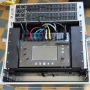 Digitální mixážní pult Allen & Heath CQ-18T v černém provedení, umístěný v transportním racku. Na přístroji jsou zapojeny barevné kabely (červený, ze…