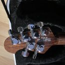 Fotografie zachycuje hlavu kytary z tmavého dřeva s chromovanými ladičkami. Na zadní straně hlavy je bílý nápis MADE IN SAN LUIS OBISPO CALIFORNIA, U…