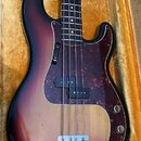 Elektrická basová kytara s tělem v tmavě červeném a žlutém sunburst provedení. Nástroj má tmavě červený pickguard s texturou, dva snímače a dvě ovlád…