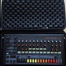 Elektronický bicí automat v černém kufru s pěnovou výplní. Na horním panelu je bílý nápis Rhythm Designer RD-8 a logo behringer. Zařízení obsahuje řa…