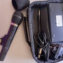 Černý dynamický mikrofon s kovovou síťkou a nápisem ELEKTRA na horní části těla. Vedle mikrofonu je otevřený černý přepravní kufr, ve kterém se nachá…