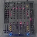 Šedočerný DJ mixér značky ALIEN&HEATH s označením :92. Přístroj obsahuje čtyři kanály s posuvníky, zahlreiche otočné knoflíky a modré podsvícené tlač…