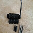 Černý kytarový kobylkový systém s páčkou. Na levé straně je viditelný nápis "Floyd Rose". Součástí jsou tři kovové pružiny a dvě černé plastové vložk…