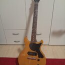Elektrická kytara s přirozeně dřevěnou barvou korpusu a černým hmatníkem. Na hlavě je bílý nápis Harley Benton. Kytara má černý pickguard, jeden sním…