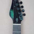 Černá hlava elektrické kytary s šesti ladicími kolíky. Na povrchu je zelené logo „Jet“ a pod ním nápis „JET GUITARS“. Povrch je glossy, s viditelnými…