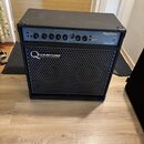Černý basový kombozesilovač s kovovou mřížkou reproduktoru. Na přední straně je bílý nápis QUANTUM BASS TECHNOLOGY. Horní ovládací panel obsahuje něk…