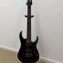 Černá elektrická kytara s šesti strunami umístěná na černém stojanu. Na hlavě je bílý nápis Ibanez. Nástroj má tmavý hmatník, dva humbuckery a most s…