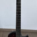 Tmavě červená elektrická kytara s dvojitými humbuckery a krčkem z tmavého dřeva. Na těle jsou dva ovládací knofíky a přepínač. Nástroj je umístěn na…