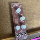 Úzký hnědý modul s bílými ovládacími knoflíky a čtyřmi zapuštěnými konektory v dolní části. Na povrchu je bílým nápisem „LADDER VCF“, nápisy „FREQ“ a…