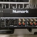 Černý DJ mixér značky Numark s nápisy SCRATCH a serato. Na předním panelu jsou vidět vstupy a výstupy s označením USB, MASTER (R, L), BOOTH, GND, CH…