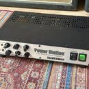 Kovový přístroj s černým horním krytem a stříbrným předním panelem. Na panelu je nápis Power Station Dual-Mode Reactance Amplifier a logo FRYETTE. Př…