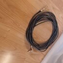 Svinutý instrumentální kabel s pleteným obalem v tmavé barvě. Kabel má na obou koncích zlaté konektory typu jack. Na kabelu nejsou viditelné žádné zn…