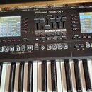 Černý digitální klavír s nápisem Roland EXPANDABLE ARRANGER E-A7. Nástroj má dvě LCD displeje, bílé klávesy a ovládací prvky v podobě tlačítek a posu…