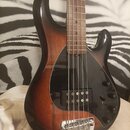 Elektrická basová kytara s pětistrunným hmatníkem a tmele hnědým povrchem v přechodu (sunburst). Nástroj má černý pickguard, jeden humbucker snímač a…