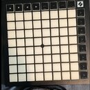 Černý MIDI kontrolér s mřížkou bíle podsvícených čtvercových padů. V horní části jsou tlačítka s popisky Session Mixer, Undo, Quantize, Custom a Capt…
