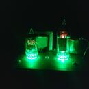 Fotografie zachycuje elektronické zařízení s dvěma vkládanými elektronkami, které jsou zespodu osvětleny zeleným světlem. Zařízení je umístěno na tma…