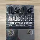 Kytarový efekt v kovovém stříbrném krytu s nápisy ANALOG CHORUS a TRUE BYPASS DOUBLE. Na horní straně jsou čtyři černé ovládací knoflíky s popisky RA…
