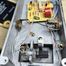 Interiér šedého kovového šasi s elektronickými komponenty. Uvnitř je umístěna baterie značky PHILIPS, základní deska s součástmi a několik potenciome…