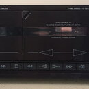 Černý kazetový přehrávač s dvěma šachtami. Na horní liště je nápis GRUNDIG, DIRECT OPERATION TECHNIQUE a TWIN CASSETTE DECK CCF 5300. Nad šachtami js…