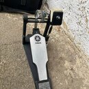 Černý basový pedál s kovovou stříbrnou deskou. Na horní části desky je umístěno logo a nápis YAMAHA. Pedál vykazuje běžné známky používání, zejména v…